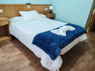 a bed with a blue blanket and two towels on it at Hostal Ponte Dos Santos in Ribadeo