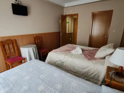 a hotel room with two beds and a television at Hostal Ponte Dos Santos in Ribadeo