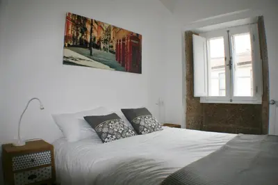 a white bed with pillows and a picture on the wall at Apartamentos Pombal in Santiago de Compostela