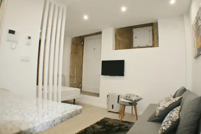 a living room with a couch and a tv on the wall at Apartamentos Pombal in Santiago de Compostela