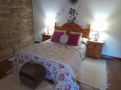 a bedroom with a bed with pink pillows on it at Caserio de Fontes in Nogueira de Ramuin