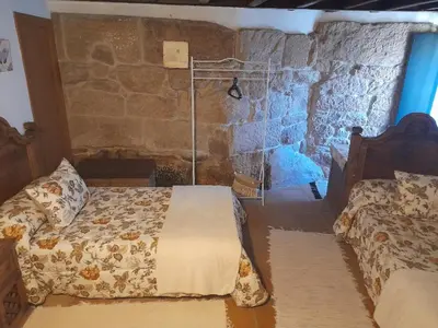 a bedroom with a bed and a stone wall at Caserio de Fontes in Nogueira de Ramuin