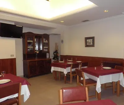 a dining room with tables and chairs and a television at Pension Restaurante La Bombilla in A Estrada