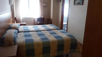 a bedroom with a bed with a blue and yellow blanket at Pension Restaurante La Bombilla in A Estrada