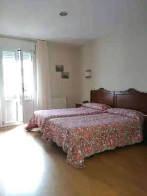 a bedroom with a bed with a red bedspread at Pension Restaurante La Bombilla in A Estrada