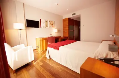 a hotel room with a bed and a chair at Hotel Ego in Viveiro