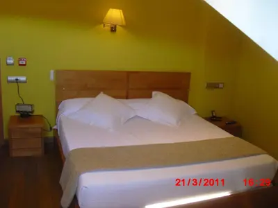 a bedroom with a white bed with green walls at Hotel O Desvio in Santiago de Compostela