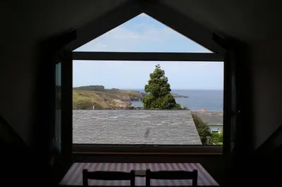 a window with two chairs looking out at the ocean at Casa Tésera in El Franco
