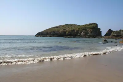 a beach with the ocean and a hill in the background at Casa Tésera in El Franco