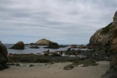 people on a beach with rocks in the water at Casa Tésera in El Franco