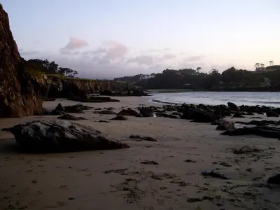 a sandy beach with rocks and the water at Casa Tésera in El Franco