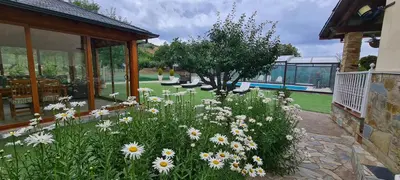 a garden with white flowers in front of a building at Casa Rural Elias in Molinaseca