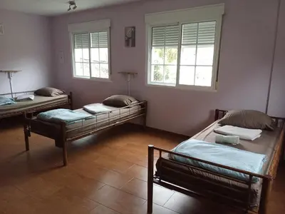 two beds in a room with two windows at Albergue o Apalpador in Melide