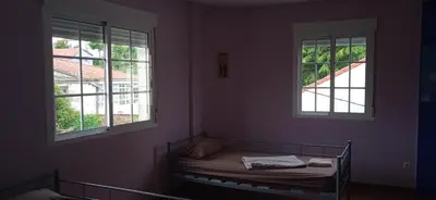 a small room with a bed and two windows at Albergue o Apalpador in Melide