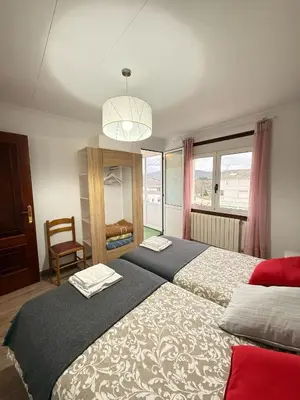 a bedroom with two beds and a chandelier at Apartamentos Portolux in Portomarin