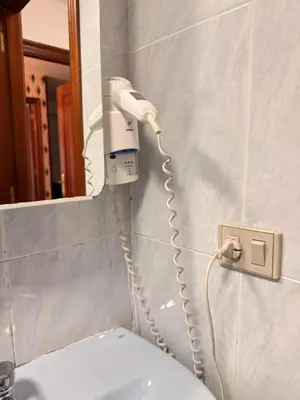a hair dryer attached to a wall next to a toilet at Apartamentos Portolux in Portomarin
