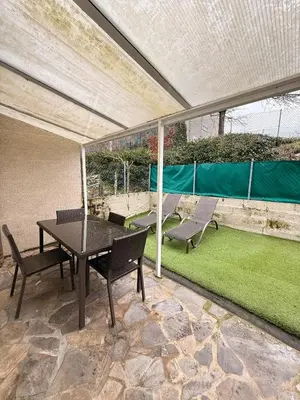 a patio with a table and chairs and grass at Apartamentos Portolux in Portomarin