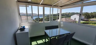 a balcony with a table and chairs and a view of the water at Apartamentos Portolux in Portomarin