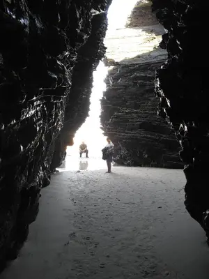 a cave with two people standing in the water at Lugomar in Foz