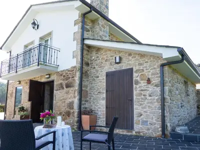 a stone house with a wooden door and a balcony at Casa Xan in Jove