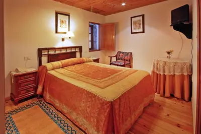 a bedroom with a bed and a table and a television at Casal de Drados in Drados