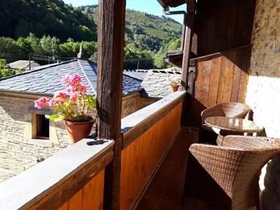 a balcony with chairs and flowers on a building at Apartamento El Valle de Oscos in Santa Eulalia de Oscos