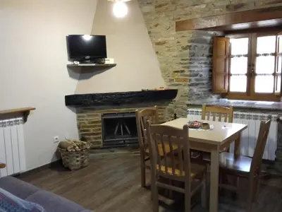 a living room with a table and a fireplace at Apartamento El Valle de Oscos in Santa Eulalia de Oscos