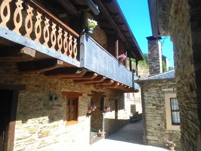 a building with a balcony with flowers on it at Apartamento El Valle de Oscos in Santa Eulalia de Oscos