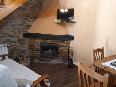 a living room with a fireplace and a tv on a wall at Apartamento El Valle de Oscos in Santa Eulalia de Oscos
