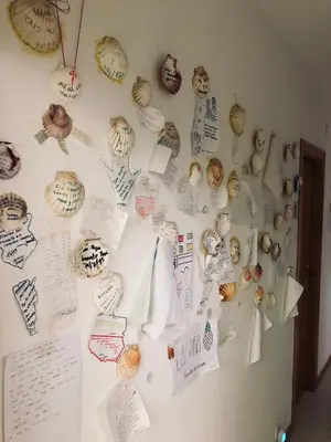a refrigerator covered in magnets and papers on a wall at Albergue la Estacion Santiago de Compostela in Santiago de Compostela