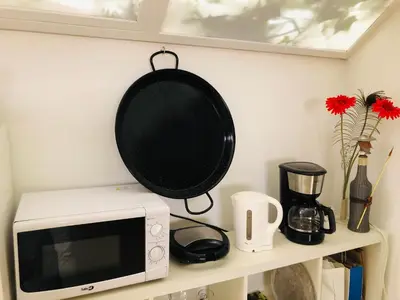 a pan hanging above a microwave on a shelf at Albergue la Estacion Santiago de Compostela in Santiago de Compostela