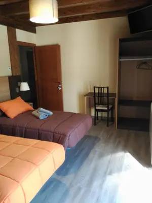 a bedroom with two beds and a table and a chair at Albergue Pension Porta Santa in Baleira