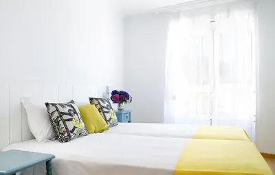 a white bedroom with a bed with yellow sheets and a window at Duerming Sea View Viveiro in Viveiro
