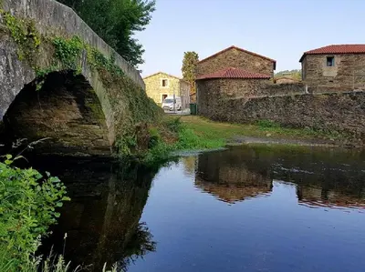 an old bridge over a river in a town at Pensión Ribadiso in Arzúa