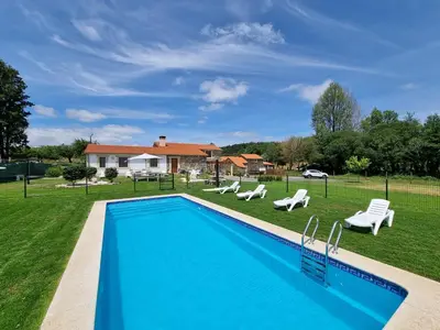 a swimming pool in a yard with chairs and a house at Pensión Ribadiso in Arzúa