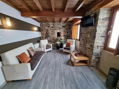 a living room with couches and a stone wall at Pensión Ribadiso in Arzúa