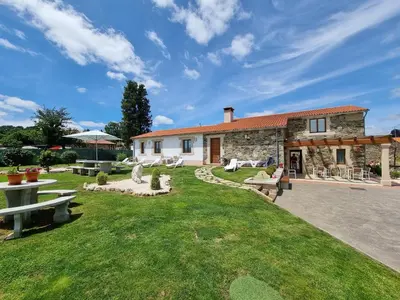 a stone house with a yard with benches and tables at Pensión Ribadiso in Arzúa