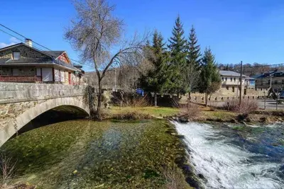 a bridge over a river with a house on it at Casas Rurales Trefacio in Trefacio