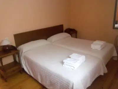 a bedroom with two beds with white sheets and towels at Hotel Las Grandas in Vistalegre