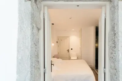 a white bedroom with two beds and a doorway at Casa Amando in Somozas