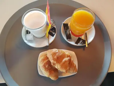 a table with two plates of food and a cup of orange juice at Pension Residencial Victoria in Santa Cruz de Ribadulla