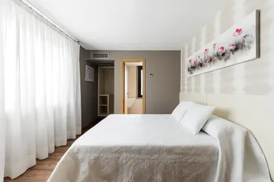 a bedroom with a large white bed with white sheets at Pension Residencial Victoria in Santa Cruz de Ribadulla