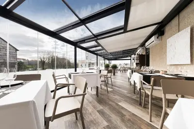 a restaurant with white tables and chairs and large windows at Pension Residencial Victoria in Santa Cruz de Ribadulla