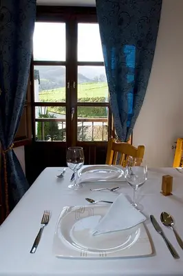 a table with a white plate and glasses on it at Hotel y apartamentos rurales L'Anceo in Cibuyo