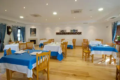 a dining room with tables and chairs with blue tablecloths at Hotel y apartamentos rurales L'Anceo in Cibuyo