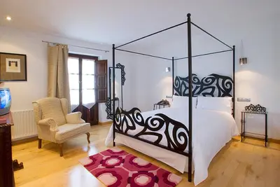 a bedroom with a canopy bed and a chair at Hotel y apartamentos rurales L'Anceo in Cibuyo