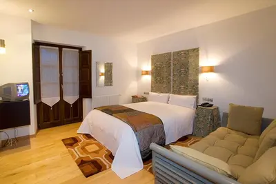 a hotel room with a bed and a couch at Hotel y apartamentos rurales L'Anceo in Cibuyo