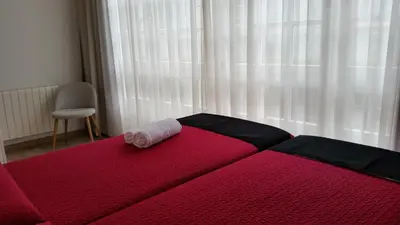 a red bed with a rolled up towel on top of it at Pensión Domus Gallery in Arzúa