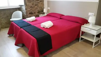 a red and black bed with two white towels on it at Pensión Domus Gallery in Arzúa