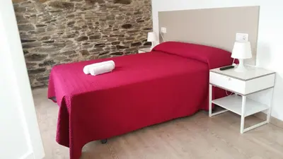 a bedroom with a red bed with a towel on it at Pensión Domus Gallery in Arzúa